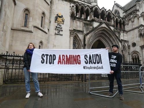 a man and a woman holding a banner 'Stop Arming Saudi'