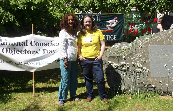 two women next to the the Conscientious Objectors' stone with white flowers