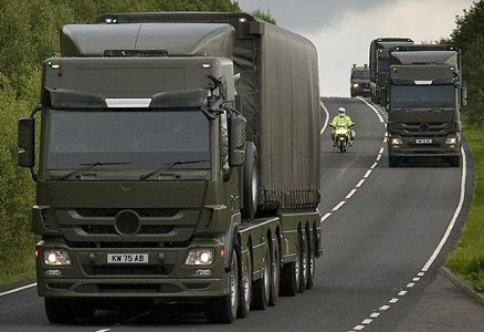 three large green lorries with escort