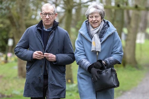 man and woman in outdoor coats with trees in the background