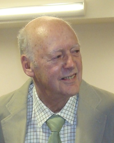 head and shoulders of a man in a check shirt, tie and jacket, looking slightly left