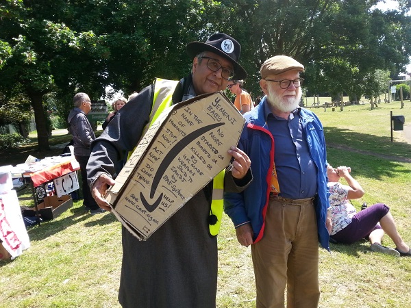Two people, one holding a cardboard coffin