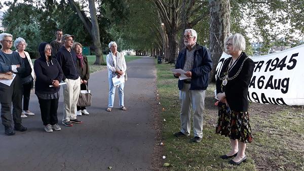 nine people standing under trees at dusk with night-lights on the ground