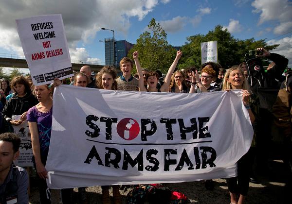 protestors in the sunshine holding a sheet banner reading Stop The Arms Fair