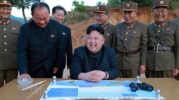a group of North Korean military officers smiling with their leader