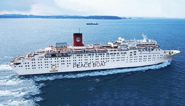 Large ocean-going boat with a single funnel and life boats and with 'Peace Boat' in large capital letters on the side