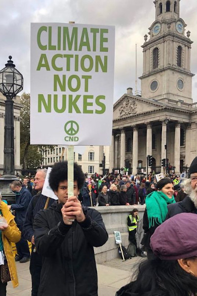 protestor holding placard reading Climate Action Not Nukes