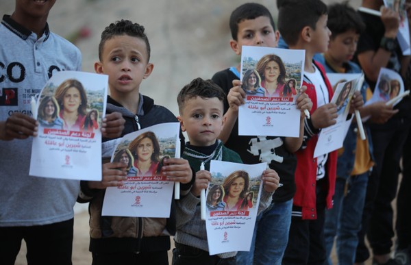 Children holding pieces of paper with photos and words in Arabic