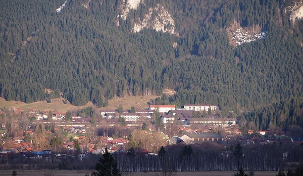 A town in front of a steep hillside with trees