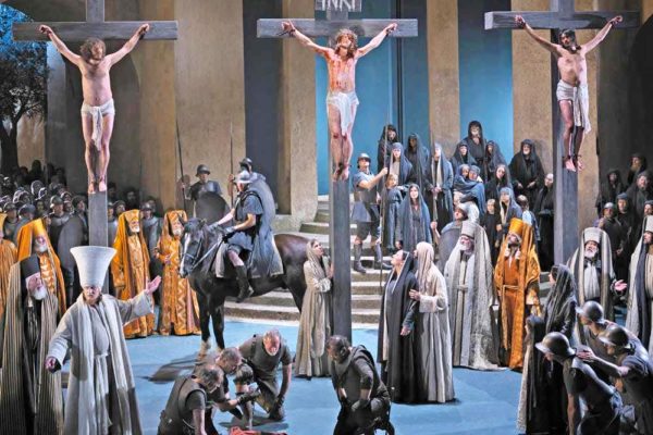 Three people on crosses with a big crowd